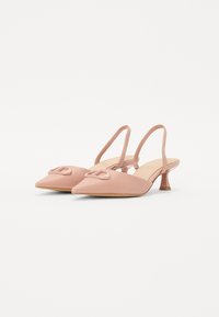Chaussures slingback roses avec un bout pointu, un petit talon carré et un accent de nœud décoratif à l'avant, fabriquées en matériau synthétique lisse.