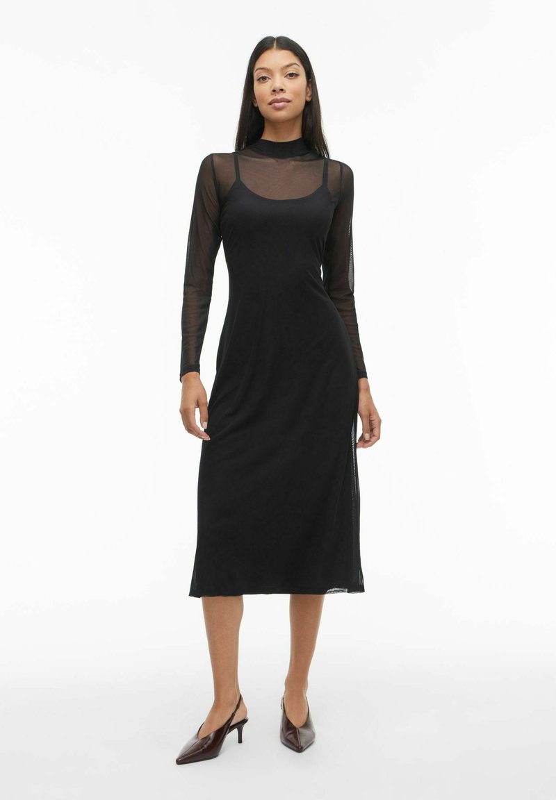 Melna midi kleita ar garām caurspīdīgām piedurknēm, apaļu kakla izgriezumu un regulējamām siksniņām. Gluda tekstūra un pieguloša siluets ar sānu šķēluma detaļu.