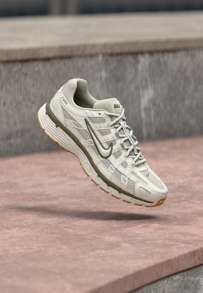 Αθλητικό παπούτσι Nike για τρέξιμο σε ανοιχτό μπεζ χρώμα με πάνω μέρος από διχτυωτό υλικό, γκρι λεπτομέρειες και εξωτερική σόλα από υφή καουτσούκ. Διαθέτει μαξιλαρωμένο περιμετρικό μέρος και δέσιμο με κορδόνια.