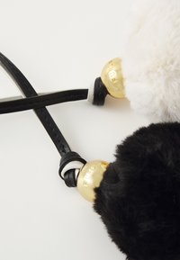 Furla keychain featuring two fluffy pom-poms in black and white with gold-tone hardware. Attached with sleek black leather straps.