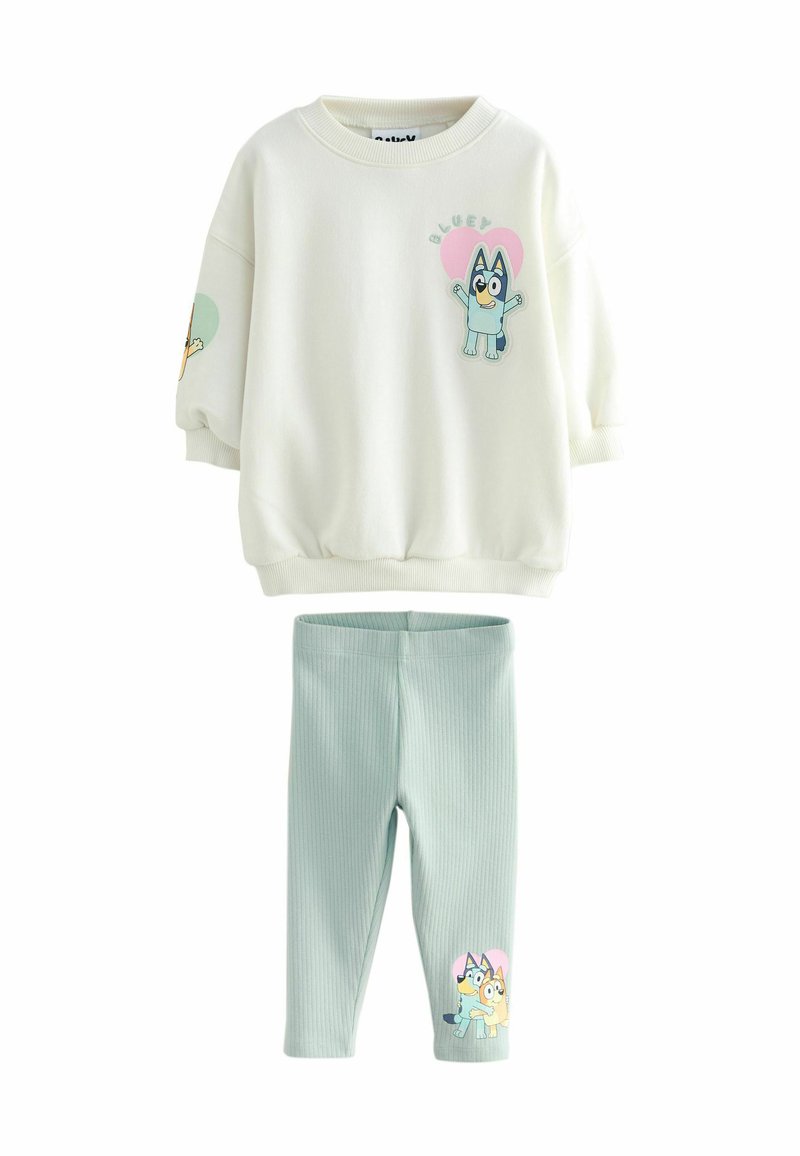 Weißes Sweatshirt mit blauem und pinkem Charakterdesign, gerippte Bündchen, kombiniert mit hellgrünen gerippten Leggings mit einem Charakterdruck.