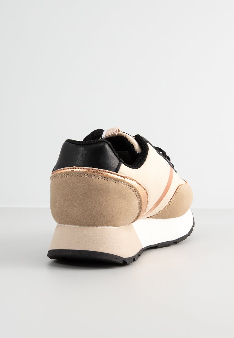 Zapatilla con un diseño en beige y negro, materiales de ante y sintético, forma redondeada y acentos contrastantes en el talón y los lados.