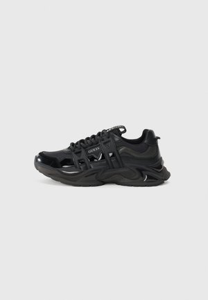 Czarne sportowe sneakersy z błyszczącym wykończeniem, siateczkowym i syntetycznym materiałem, masywną falistą podeszwą oraz wyciętymi akcentami. Logo na języku.