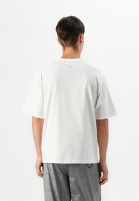 White short-sleeve t-shirt made from cotton with a crew neckline, featuring a small pink logo on the upper back.
