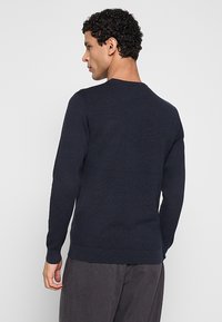 Marineblauwe gebreide trui met een gestructureerd patroon, een ronde halslijn en geribbelde manchetten en zoom. Getailleerd model, gemaakt van flexibel, zacht materiaal.