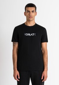 Camiseta de algodón negra con logo metálico en plata "MORATO" en el pecho, cuello redondo clásico y mangas cortas.