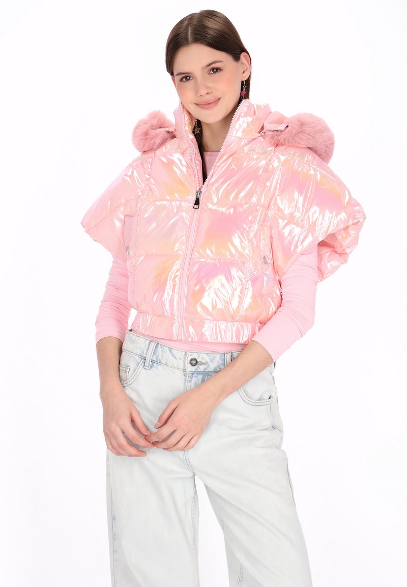 Perłowo-różowa pikowana kurtka z przednim zamkiem błyskawicznym, dużym kapturem i ozdobami z pomponów z sztucznego futra. W połączeniu z jasnymi jeansami.