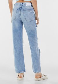 Ljusblå högmidjade denimjeans med rak benstil, med rivna detaljer och en baketikett märkt "Bershka."