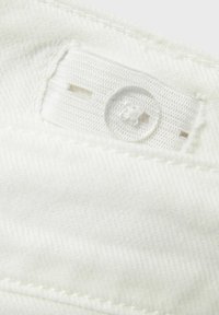 Adjustable white fabric strap with a clear plastic button sewn onto white textured clothing material.
