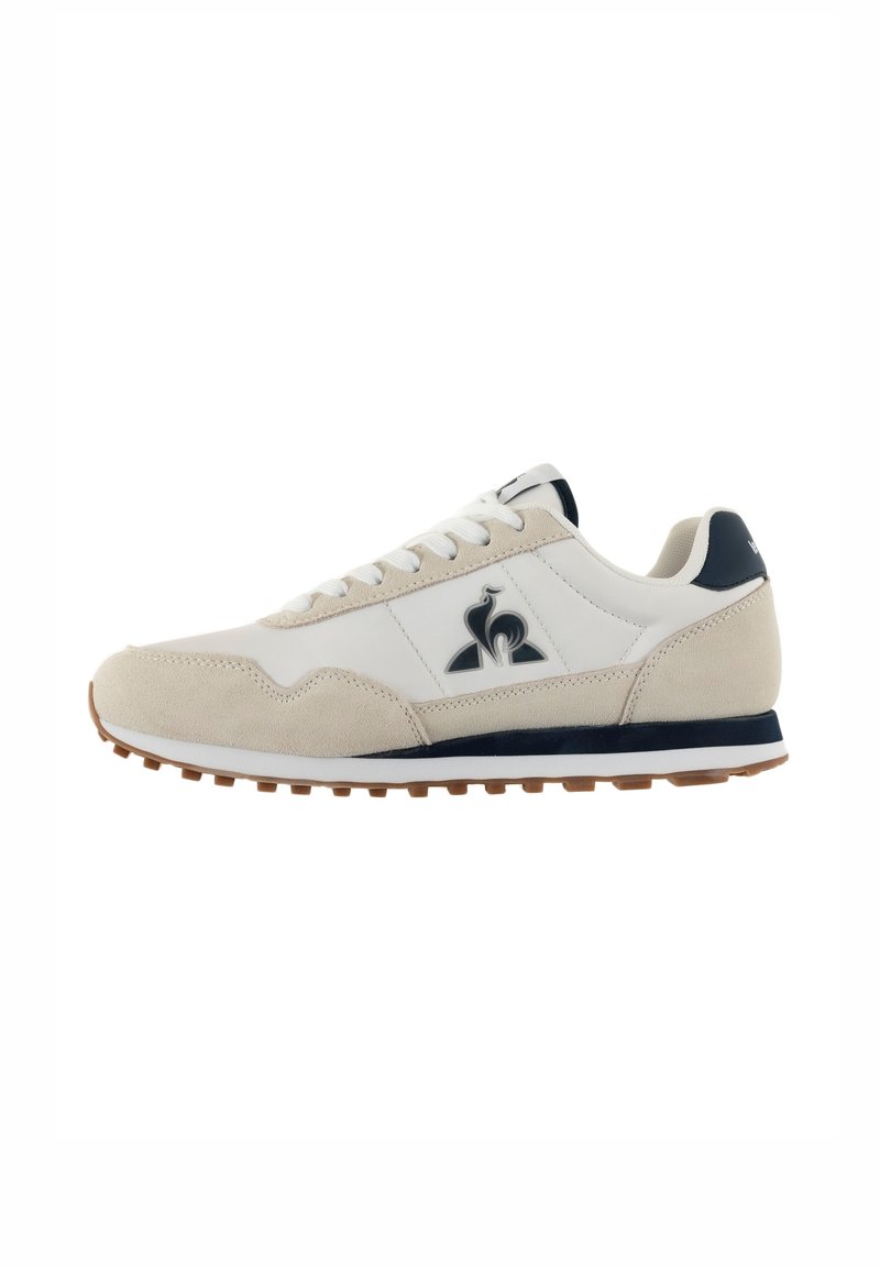 Sneaker beige e bianco con tomaia in suede e sintetico, chiusura con lacci, accenti blu marino e suola in gomma ammortizzata.