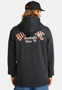 Zwarte hoodie met een grote graphic op de achterkant met kleurrijke tekst: "BILLABONG Australia Since 73". Katoenmix, aansluitend ontwerp.