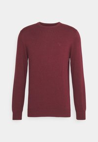 Pull en maille bordeaux à manches longues, col rond et poignets côtelés ; présente un petit logo brodé sur le haut de la poitrine gauche.