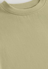 Olivgrön t-shirt med kort ärm och rund halsringning. Slät bomullstyg som erbjuder en mjuk textur och jämn sömnad runt kragen.