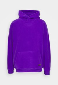 Violetti fleecetakki etutaskulla, rennolla istuvuudella ja resorihihoilla. Varustettu nyörisä hupulla ja teksturoidulla kankaalla.