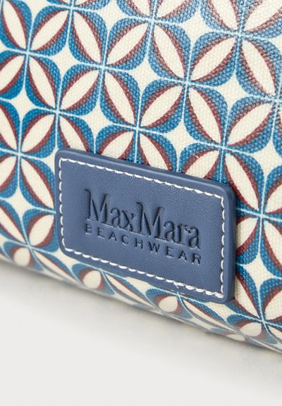 Γεωμετρικό μοτίβο σε μπλε και κόκκινο σε ύφασμα με ετικέτα ραμμένη σε ναυτικό μπλε που γράφει "Max Mara Beachwear".