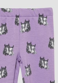 Fioletowe legginsy wykonane z miękkiego materiału, z powtarzającym się wzorem szarych i czarnych głów koni. Gładka faktura, elastyczny pas.