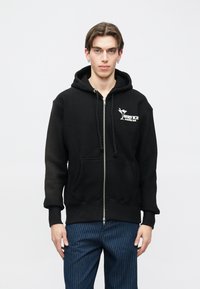 Čierna mikina na zips s prednými vreckami, kapucňou so šnúrkami a bielou potlačou na hrudi s nápisom "SERVICE MARGINI BAR".