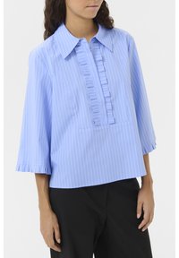 Light blue, vertical striped blouse with a ruffled placket, pointed collar, and three-quarter sleeves with ruffled edges.
