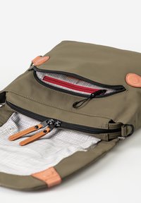 Borsa verde oliva con esterno morbido, dettagli in pelle, due scomparti con cerniera e fodera interna a quadri.