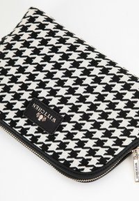 Clutch con motivo a zig zag in tessuto bianco e nero, con una patch in pelle nera e hardware della cerniera tono oro.