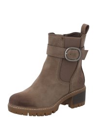 Stivale ankle in suede marrone con punta rotonda, pannelli laterali elastici e un accento in metallo a fibbia. Presenta un tacco spesso e suola in gomma testurizzata.