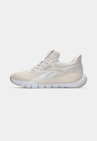 Ljust beige träningsskor med överdel av andningsbart mesh, vita detaljer och en vadderad sula med segmenterade spår för flexibilitet.