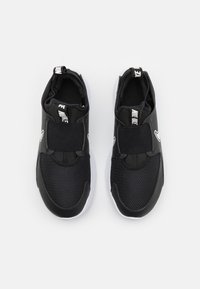 Black athletic shoes with mesh upper, elastic band closure, and white rubber sole. Features minimalistic design and no laces.