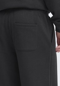 Dark grey sweatpants featuring a side pocket, soft texture, elastic waistband, and straight-leg design.