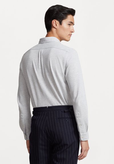 Gray long-sleeve shirt with a button-down collar, featuring a subtle texture. Paired with navy pinstriped trousers, displayed from the back.