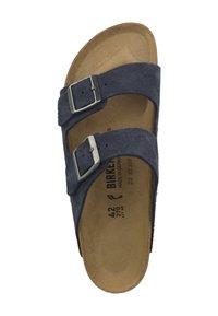 Mörkblå mockasandaler med två justerbara silverfärgad spännen, konturerad beige sula och mjuka kanter. Storleken är markerad som 42.