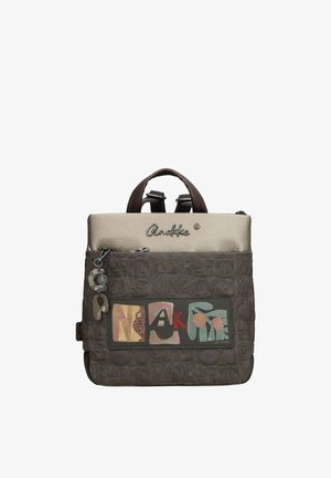 Zaino marrone quadrato con manico superiore, tasca frontale con cerniera, toppa colorata con la scritta "ANEKKE" e portachiavi decorativo.