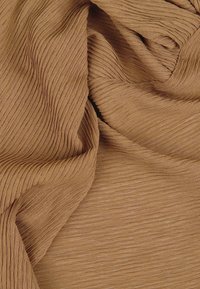 Tessuto strutturato di colore marrone chiaro con sottili strisce verticali, caratterizzato da un design morbido e plissettato e una finitura liscia e leggermente lucida.