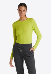 Långärmad topp i ljus limegrön ribbad tyg, kombinerad med kolsvartra sweatpants med justerbar dragsko i midjan.