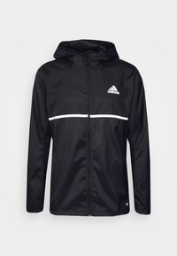 Svart Adidas lättviktsjacka med huva, vit horisontell rand över bröstet och framzipper.