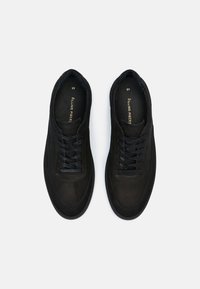 Paire de baskets noires en cuir à lacets, taille 45, avec "Filling Pieces" imprimé en or à l'intérieur de chaque chaussure sur un fond blanc.