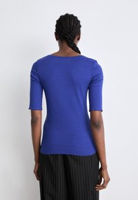 Azuurblauw top met korte mouwen en een ronde halslijn, met een aansluitende pasvorm, gemaakt van een soepele, rekbare stof.