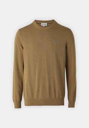 Brązowy sweter z dzianiny z długimi rękawami, okrągłym dekoltem oraz prążkowanymi mankietami i dołem. Na piersi znajduje się małe zielone logo Lacoste.