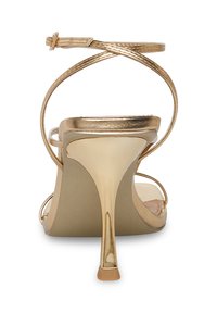 Guldmetallic stiletto med smalle ankelremme, åben tå og elegant hæl. Glat tekstur og minimalistisk design.