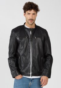 Schwarze Lederjacke mit einem Reißverschluss vorne, zwei Brusttaschen und seitlichen Reißverschlüssen. Sie verfügt über einen Stehkragen und subtil strukturierte Akzente.