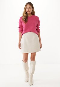Różowy puszysty sweter, kremowa teksturowana mini spódnica i białe kozaki do kolan. Prosty design i miękkie materiały tworzą spójną stylizację.