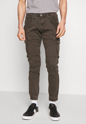Pantaloni cargo în verde închis, cu picioare conice, multiple buzunare laterale, accente cusute și închidere cu buton. Textură de țesătură rezistentă.