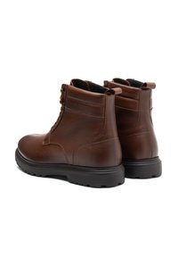 Bocanci de gleznă din piele maro cu un finisaj texturat, guler căptușit, vârf rotund și talpă din cauciuc negru. Au cusături minime și ochiuri din metal.