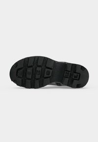 Semelle de botte en caoutchouc noir avec des crampons profonds et des motifs rectangulaires en relief, affichant le mot « DIESL » incrusté dans les rainures.