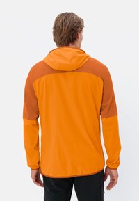 Veste légère orange avec des accents marron, une capuche et un ourlet élastique. Elle possède des manches longues et une texture lisse et mate.