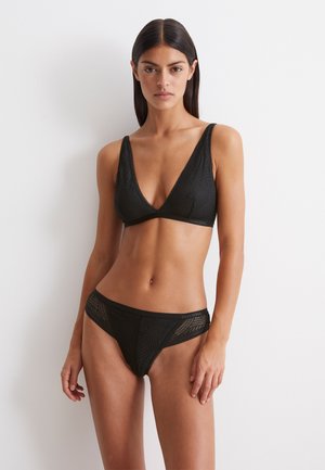 Zwart bikini set bestaande uit een triangulaire bralette met een textuurpatroon en bijpassende low-rise slip. Gemaakt van een zachte, rekbare stof.
