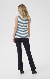 Blue and white striped sleeveless top with a scalloped hem, paired with dark flared jeans and black heeled boots.