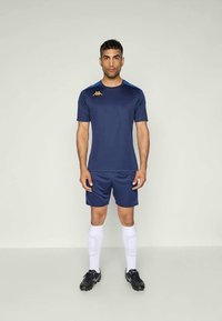 Navy blue athletic jersey and shorts made from lightweight fabric. Features gold logo on chest, short sleeves, and white socks.