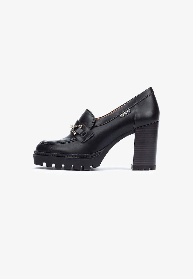 Mocassin à talon haut en cuir noir avec semelle épaisse, détail boucle dorée, et talon bloc empilé, vu de côté sur fond blanc.