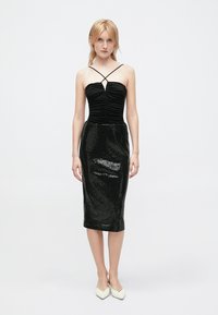 Vestido preto sem alças com corpete franzido, saia justa de lantejoulas, comprimento até ao joelho, textura suave e finas alças em cruz.