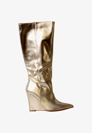 Botte compensée dorée brillante montant jusqu’au genou avec bout pointu et texture cuir lisse, vue de profil.